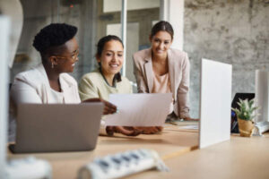 Happy Female Entrepreneurs Cooperating While Analyzing Business Plans In The Office. - ContSmart Contabilidade e Corretora de Seguros